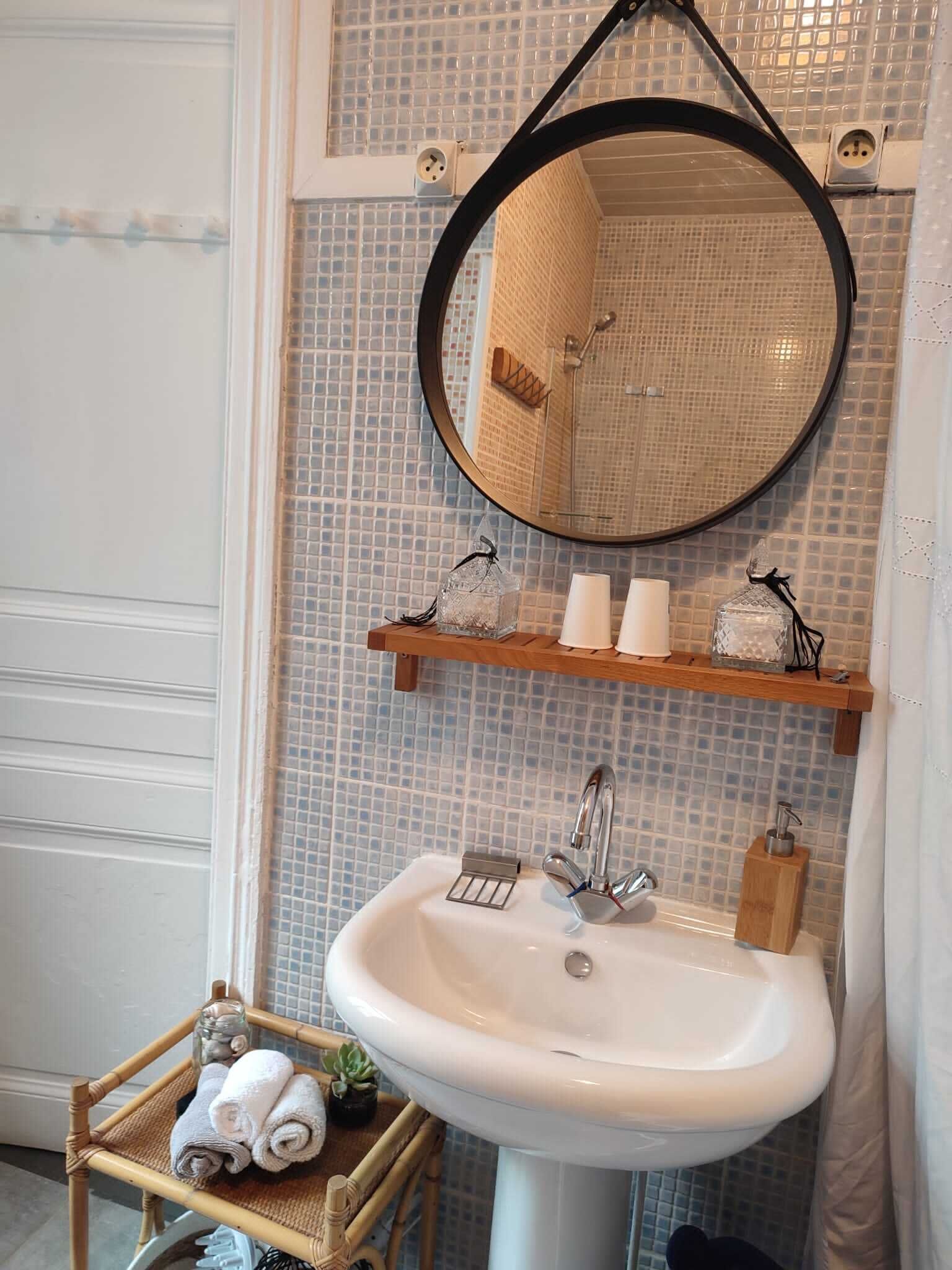 A bathroom with a white sink, a mirror, and a shelf with toiletries.