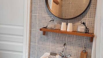 A bathroom with a white sink, a mirror, and a shelf with toiletries.