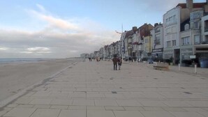 Eine breite Promenade mit Strand auf einer Seite und Gebäuden auf der anderen.