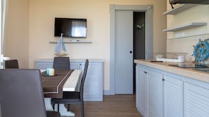 A dining area with a table, chairs, and a television mounted on the wall.