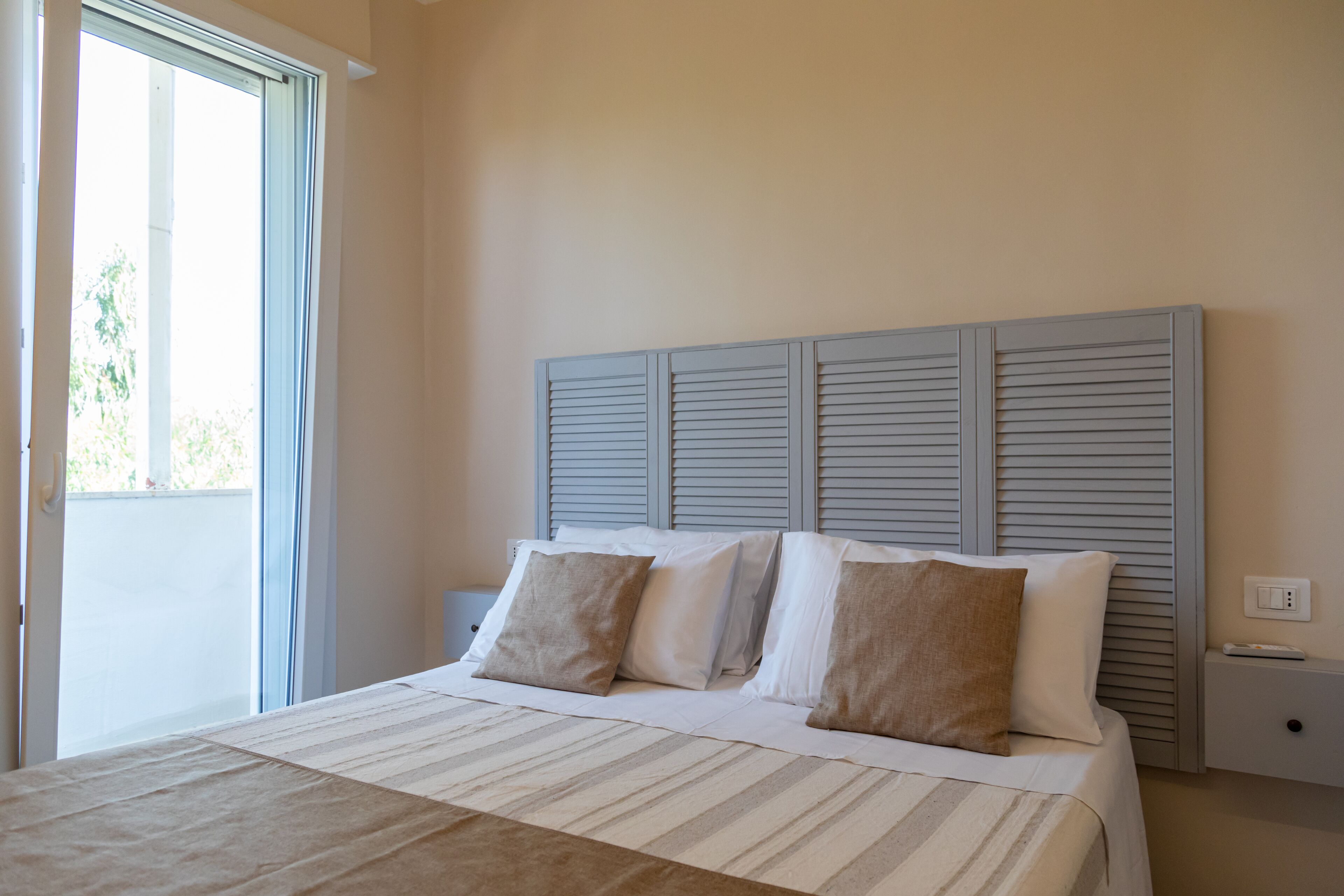 A bedroom with a bed, a headboard, and a nightstand.