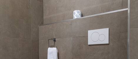 A modern bathroom with a bidet, toilet, towel rack, and a wall-mounted toilet paper holder.