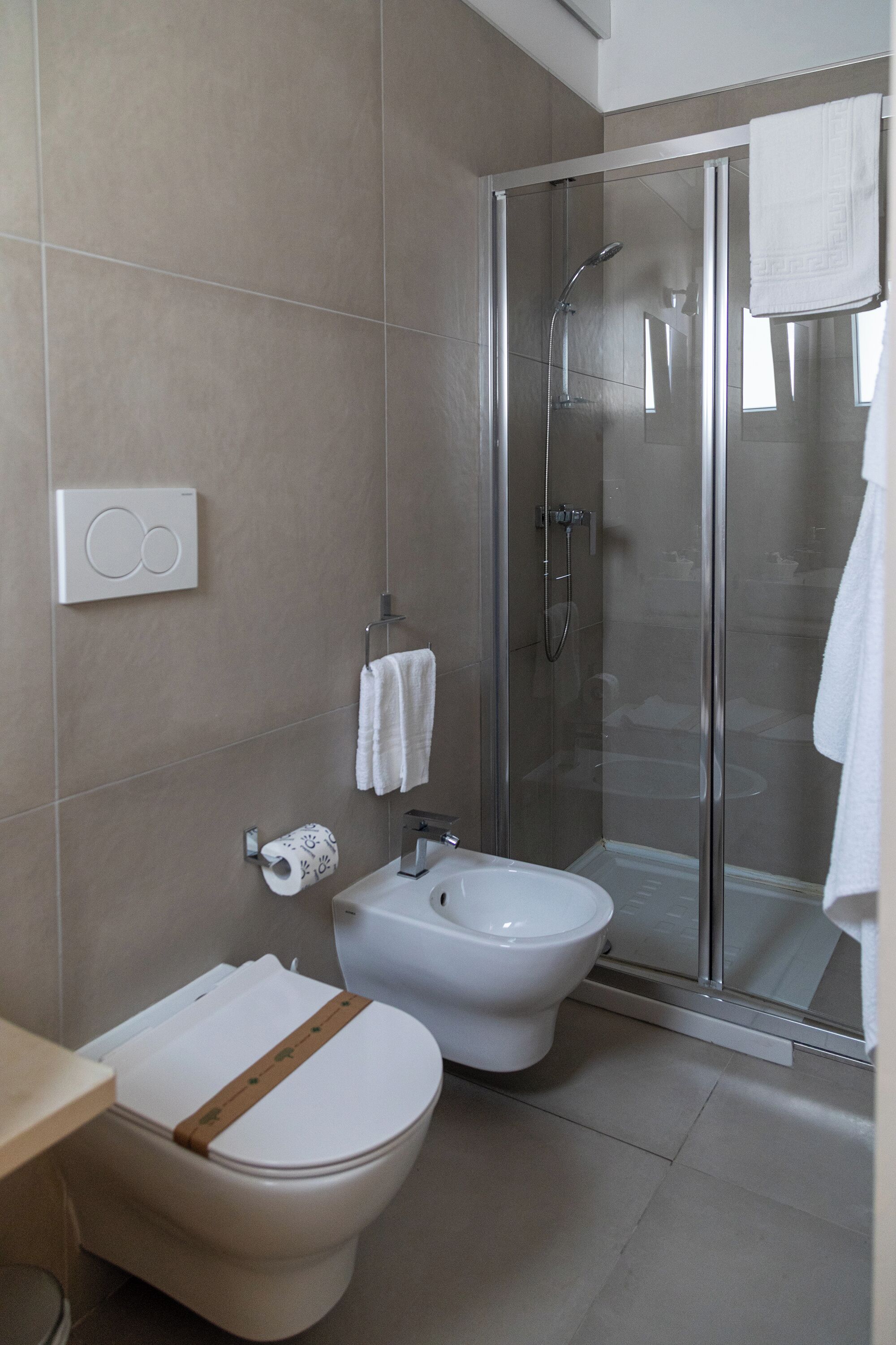 Une salle de bain moderne équipée de toilettes, d’un bidet et d’une douche à parois de verre.