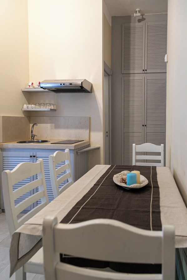 A compact kitchen with a sink, stove, and a dining area with a table and chairs. - Lido degli Angeli Case Vacanza & Beach (Porto Cesareo)