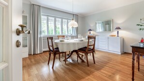 Un coin repas avec une table ronde, des chaises en bois et une nappe blanche.