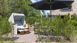 Een terras met een lounge stoel, een tafeltje en een grote parasol.