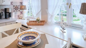 A kitchen with white cabinets, a coffee maker, a wicker basket, and a small sailboat model. - Dieses Friesische Domizil Befindet Sich in Ruhiger Lage im Ortsteil Keitum (Sylt / OT Keitum)