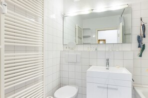A modern bathroom with a toilet, sink, shower, and towel rack.