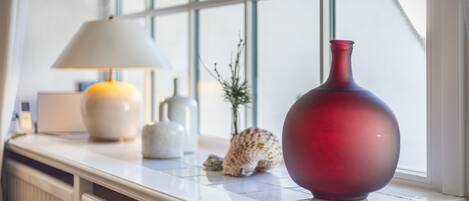 Een marmeren aanrecht met een rode vaas, een witte lamp en een decoratieve schelp.
