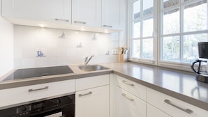 Eine moderne Küche mit weißen Schränken, einem eingebauten Herd und einem großen Fenster, das für natürliches Licht sorgt.