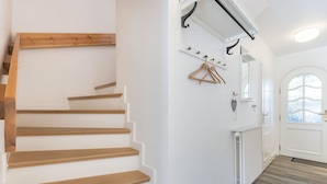 Eine Treppe mit Holzboden und einer weißen Wand, ein Heizkörper und eine Tür mit Fenster.
