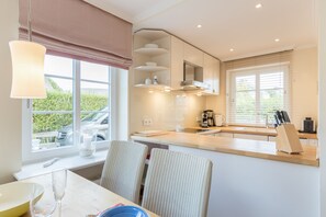 Una cocina moderna con comedor, que cuenta con un amplio ventanal, armarios empotrados y encimera de madera.