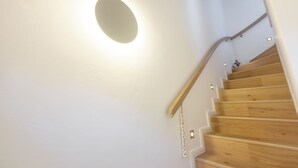 Uma escada de madeira com uma parede branca e um aparelho de iluminação.