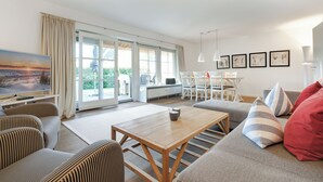 Un salon spacieux avec une table basse en bois, des canapés à rayures et une grande fenêtre agrémentée de rideaux.