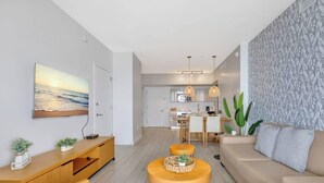 Un salon moderne comprenant un canapé, une table basse, un téléviseur et un coin repas avec une table et des chaises.
