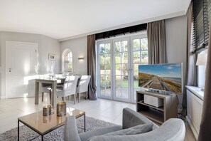 Relax in this stylish living room with a large flat-screen TV, comfortable sofa, and dining area.