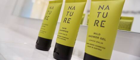 Three Nature brand hair shampoo and shower gel tubes on a white surface.
