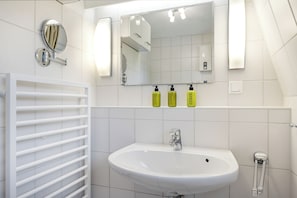 A bathroom with a white sink, mirror, and towel rack.