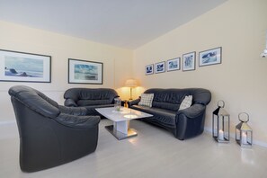 A modern living room with a sofa set, a coffee table, and wall-mounted pictures.