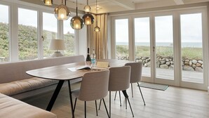 Un comedor moderno con una mesa redonda, asientos acolchados e iluminación colgante.