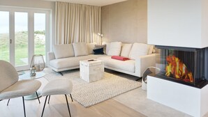 Una sala de estar moderna con chimenea, un sofá, una mesa de centro y vistas al exterior.