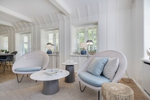 A modern living room with wicker furniture, a marble coffee table, and a round wooden side table. - Käptn's Hüs - generously proportioned apartment over two levels (Sylt / OT Keitum)
