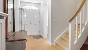 A hallway with a wooden bench, a coat rack, and a door with a window.