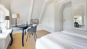 A bedroom with a bed, a desk, a chair, and a television.