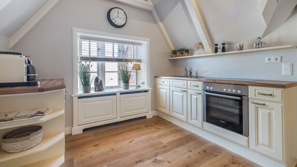 A kitchen with a wooden countertop, a Bosch oven, and a window with blinds.