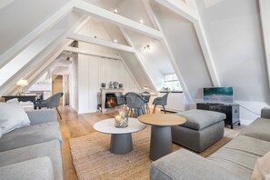 Un loft espacioso con techos altos, chimenea, mobiliario moderno y un amplio ventanal.