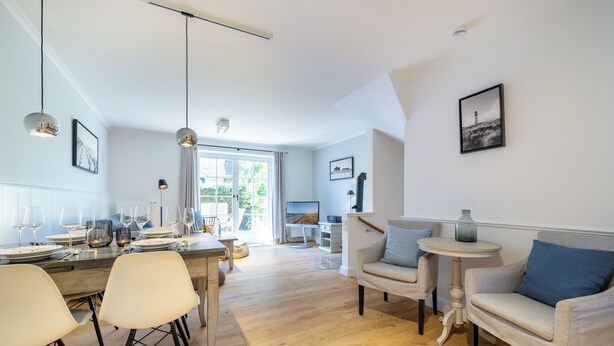 Un moderno salón con comedor, suelo de madera y vistas al exterior.