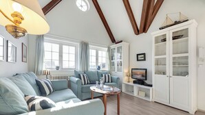 Un salon comprenant un canapé, une table basse, un téléviseur et un meuble avec des portes en verre.