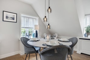 A dining area with a round table, wicker chairs, and pendant lighting. - Großzügig Geschnittene Og-wohnung im Historischen Kern von Keitum (Sylt / OT Keitum)