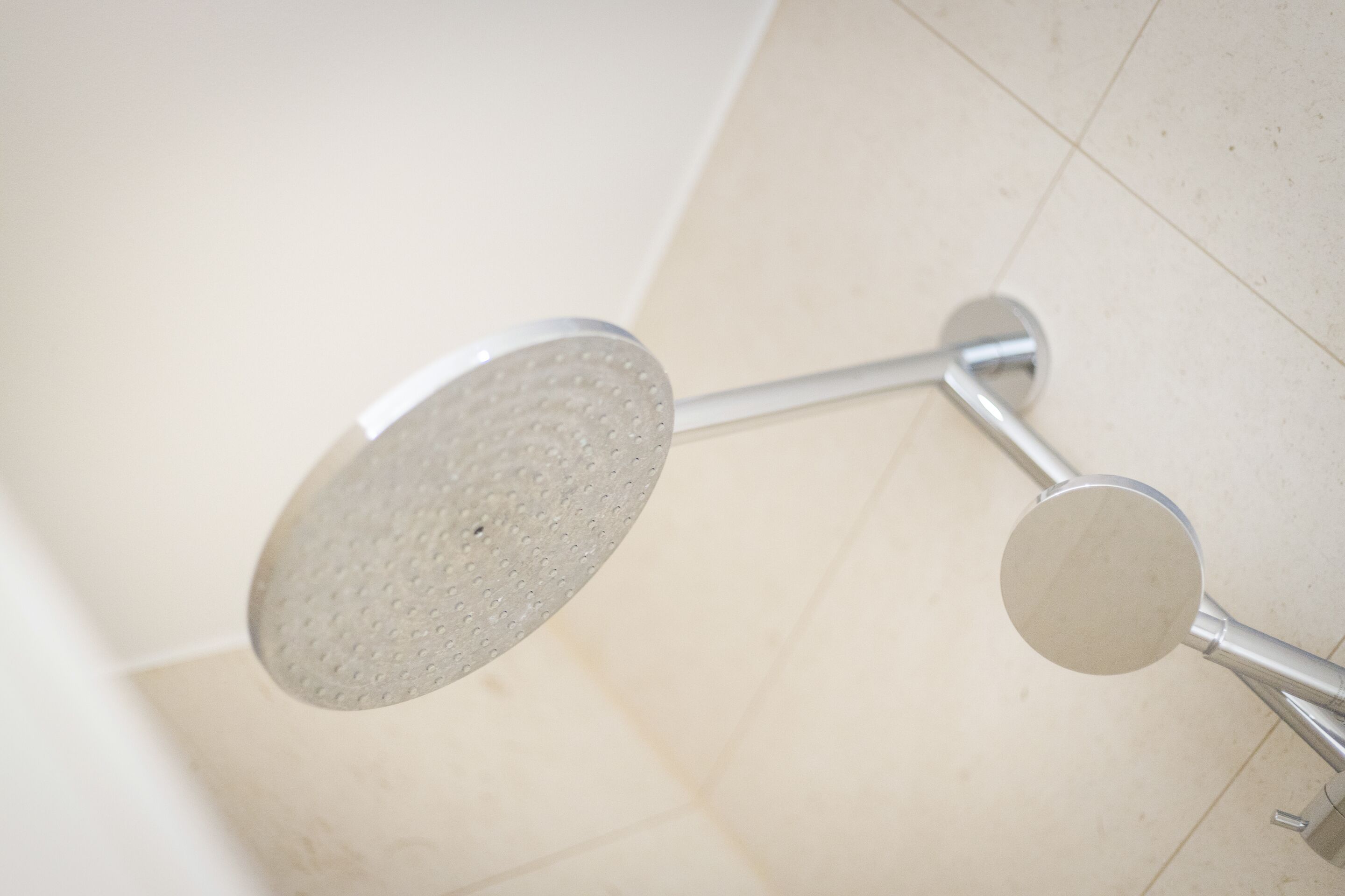 A shower with a handheld showerhead and a wall-mounted faucet.