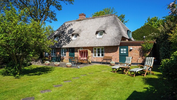 A thatched-roof house with a brick exterior, a lawn, and outdoor seating. - Restauriertes, Unter Denkmalschutz Stehendes Reetdach-einzelhaus der Extraklasse (Sylt / OT Keitum)