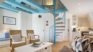 Una sala moderna con muebles de mimbre, una mesa de centro blanca y una escalera azul.