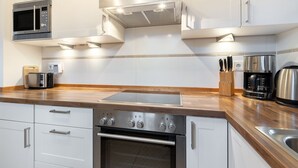 A modern kitchen with stainless steel appliances, wooden countertops, and white cabinetry. - Ein Romantisches Reetdachhaus im Historischen Ortskern von Keitum (Sylt / OT Keitum)