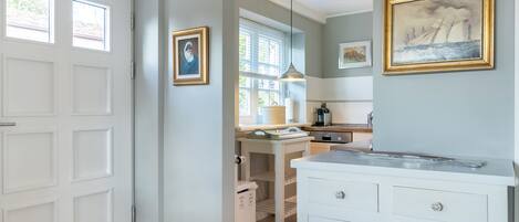 A kitchen with white cabinets, a countertop, and a hanging light fixture.