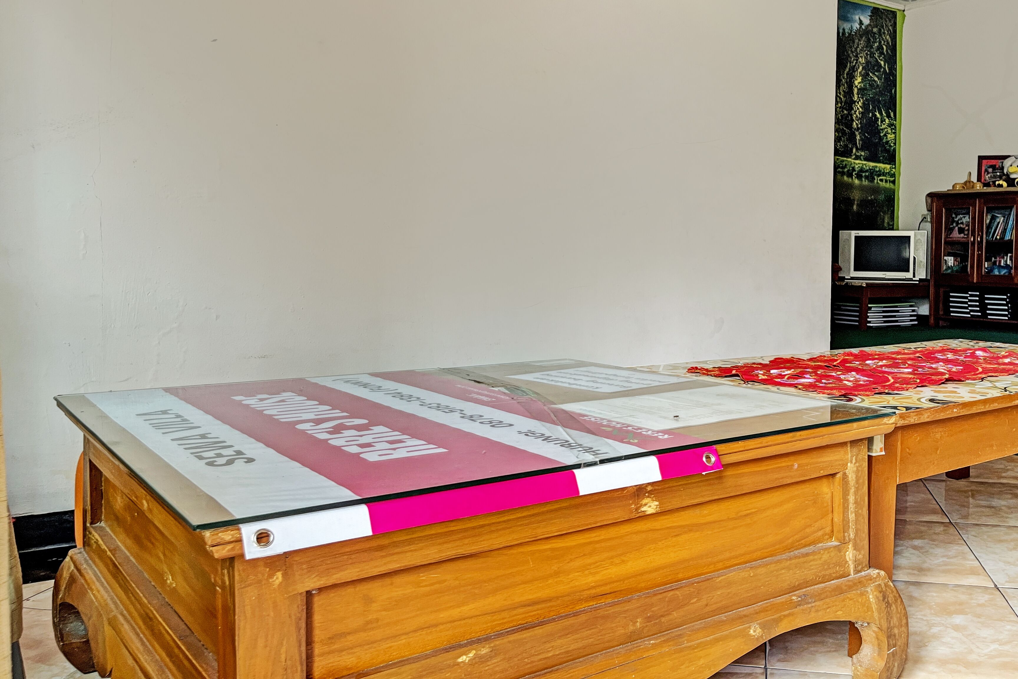 Un escritorio de madera con cubierta de vidrio y un cartel promocional rosa y blanco.