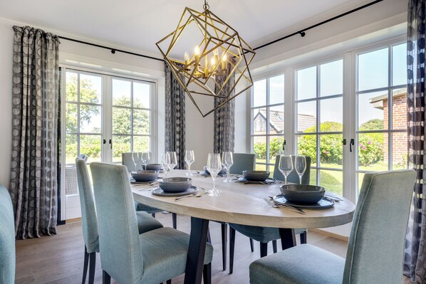 A dining area with a round table, chairs, and a chandelier.