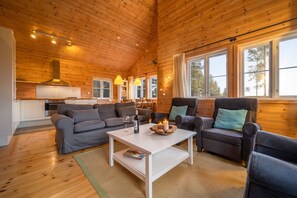 Een gezellig chaletinterieur met een houten plafond, een keukenhoek en zithoek met een salontafel.