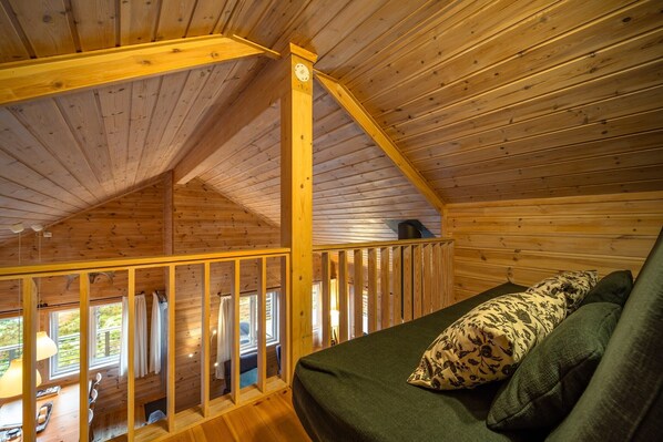 Een houten blokhut met een slaapkamer op een entresol, een balkon en uitzicht op de omgeving.