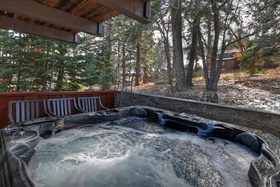 Un bain à remous avec une terrasse en bois et une vue sur les arbres.