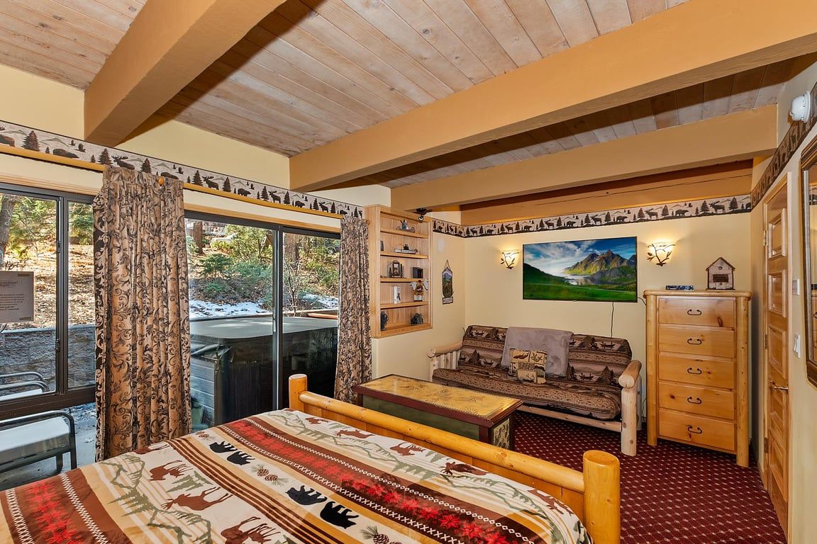 Een gezellige kamer met een bed, een bank, een houten dressoir en een schilderij aan de muur.