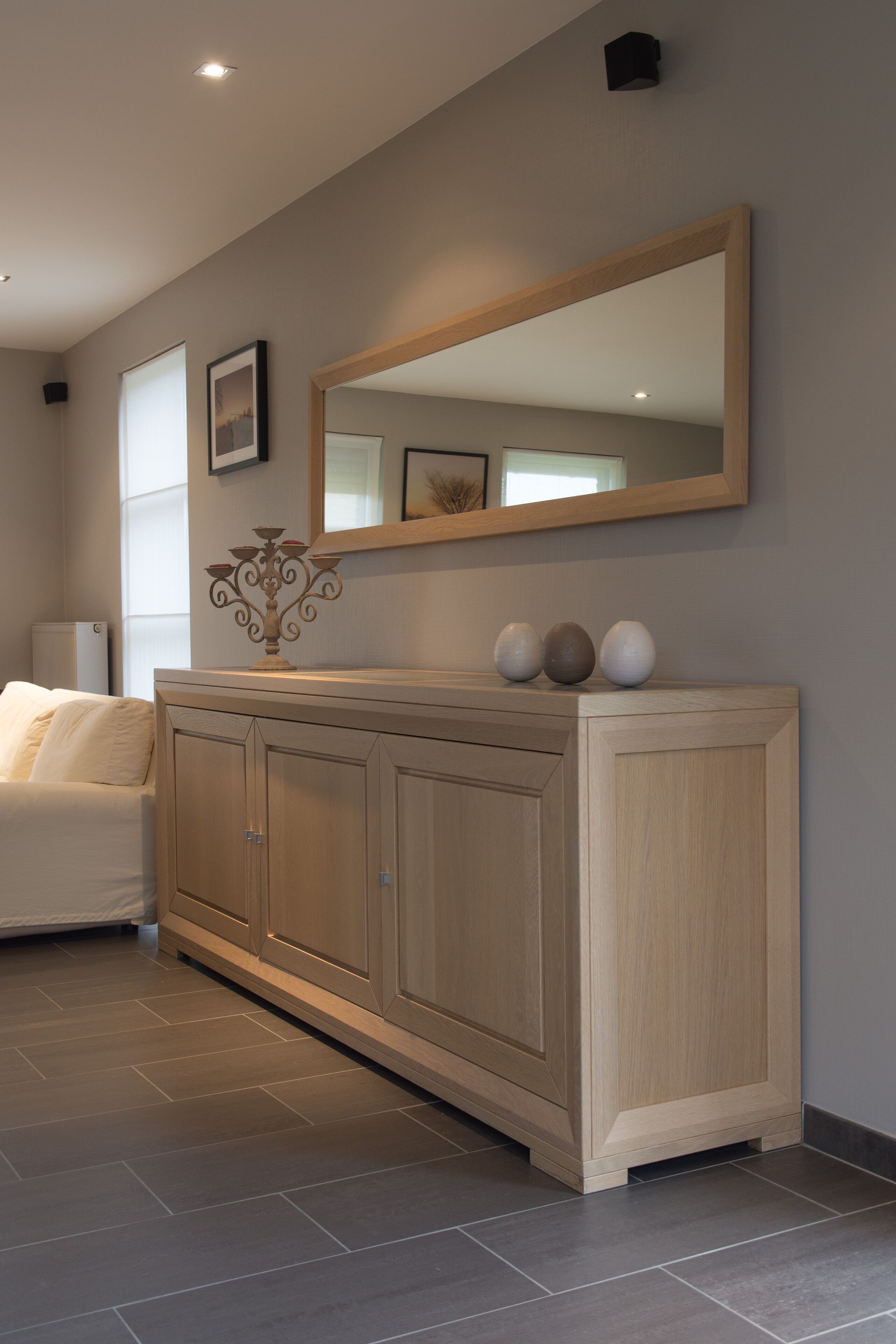Une salle de bain moderne avec un grand miroir, un meuble agrémenté d’objets décoratifs et une baignoire blanche.