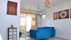 A modern living room with a blue sofa, a wooden cabinet, and decorative wall art. - Mia Homes Mombasa (Mombasa)