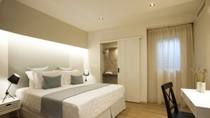 A modern hotel room with a neatly made bed, a desk, and a chair.