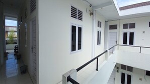 Un immeuble à plusieurs étages, aux murs blancs, doté de nombreuses fenêtres et d’un balcon.