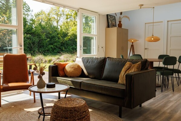 A modern living room with a leather sofa, a round coffee table, and a dining area with a table and chairs.