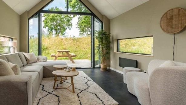 A modern living room with a large window, a sofa, a coffee table, and a TV.